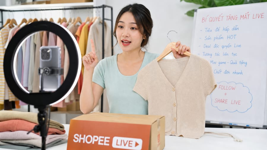 Tối ưu nội dung phiên live giúp tăng mắt live Shopee ổn định Người bán livestream trên Shopee với biểu đồ tăng mắt live Shopee trên màn hình điện thoại